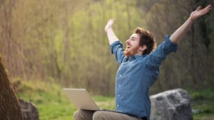 Happy hipster with laptop in the forest